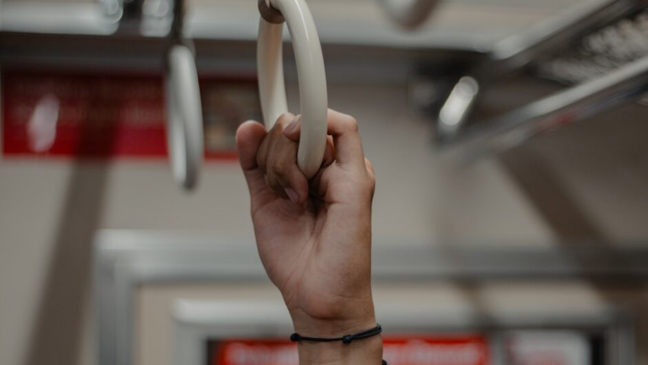 電車のつり革につかまる男性