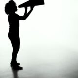 メガホンを掲げて呼びかける人のシルエット