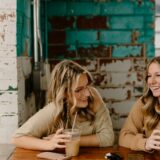 飲み物を前にテーブルに座る二人の女性