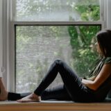 窓辺で考えごとをする女性