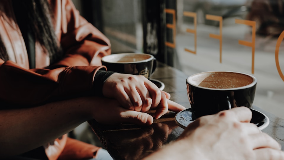 窓辺でコーヒー片手に会話する二人