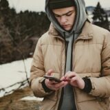 コートを着てスマホを持つ人