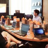 ノートPCを前にした人々の前に立つ男性