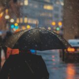 激しい雨の中を傘をさして歩く人