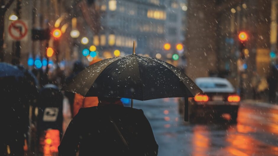激しい雨の中を傘をさして歩く人