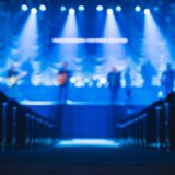 青いライトのステージに立つ出演者