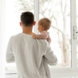子どもを抱いて窓の外を見る父親