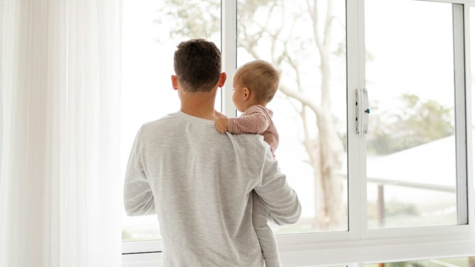 子どもを抱いて窓の外を見る父親