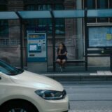 街のバス停でバスを待つ女性