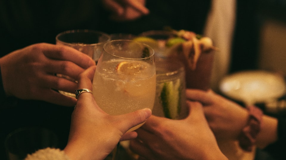 お酒のグラスを片手に持つ人
