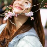 満開の桜の下で微笑む女性