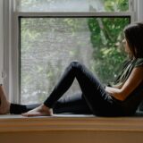 窓辺でぼんやり過ごす女性