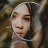 手鏡で自分を見つめる女性