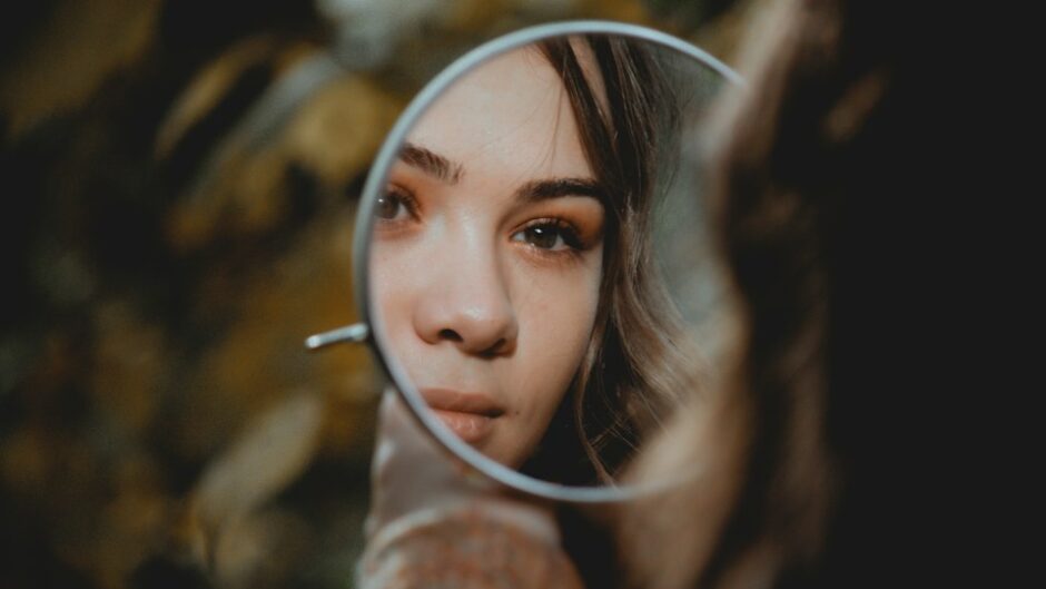 手鏡で自分を見つめる女性