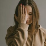woman covering her face, feeling overwhelmed