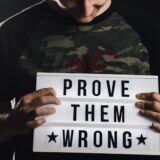 man holding a prove them wrong sign