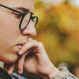 boy holding his face while thinking hard