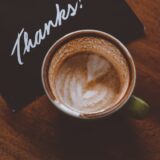 thanks a bunchというお礼のメッセージカードとコーヒーが置かれたテーブルのイメージ