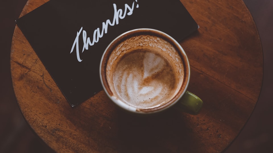 thanks a bunchというお礼のメッセージカードとコーヒーが置かれたテーブルのイメージ