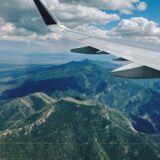 空を飛ぶ飛行機の翼と眼下の景色のイメージ