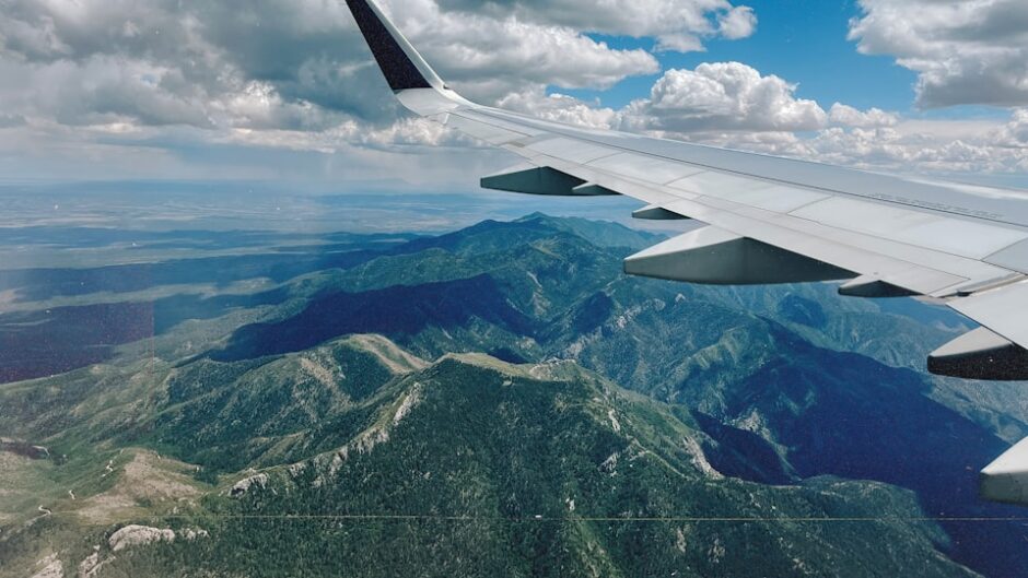空を飛ぶ飛行機の翼と眼下の景色のイメージ