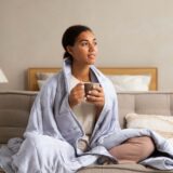 ソファで温かい飲み物を持つ人
