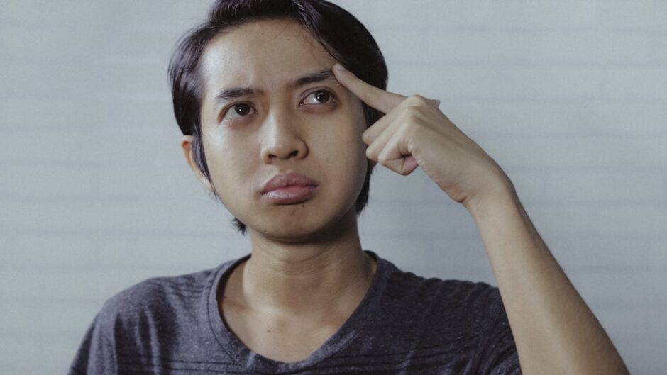 首をかしげて考え込む男性