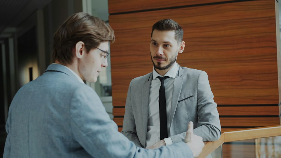 手すり付近で立ち話をする二人の男性