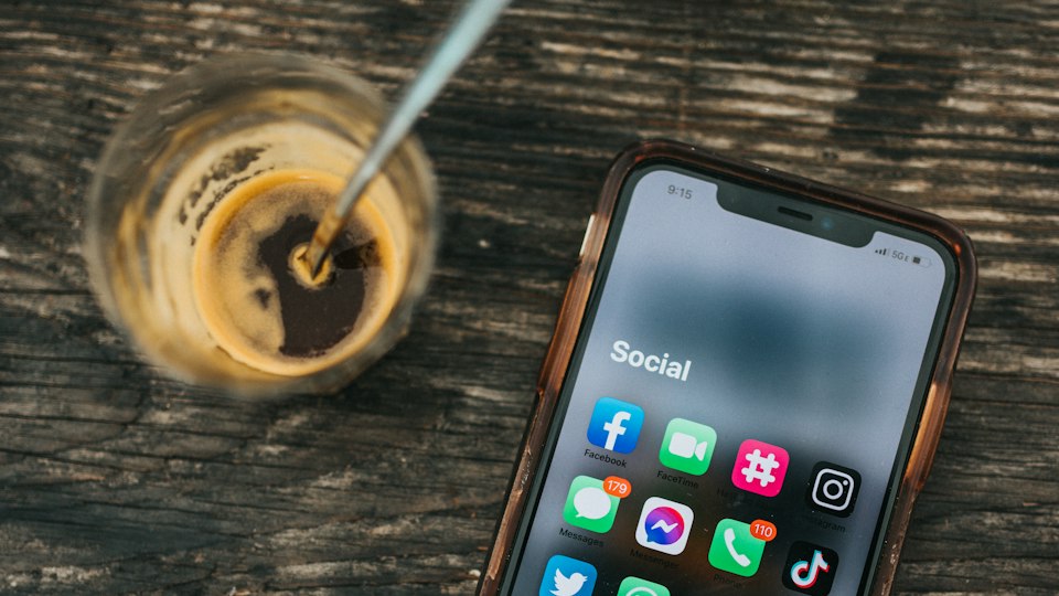 SNSアプリが表示されたスマートフォンとコーヒー