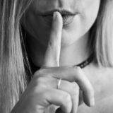静かにするよう指を口に当てる女性