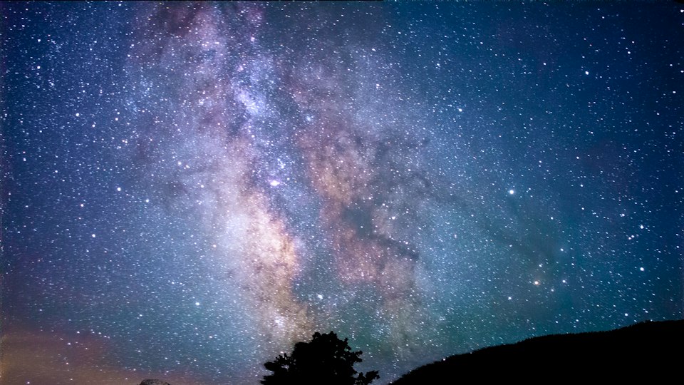 夜空の下にそびえる山と木々のシルエット