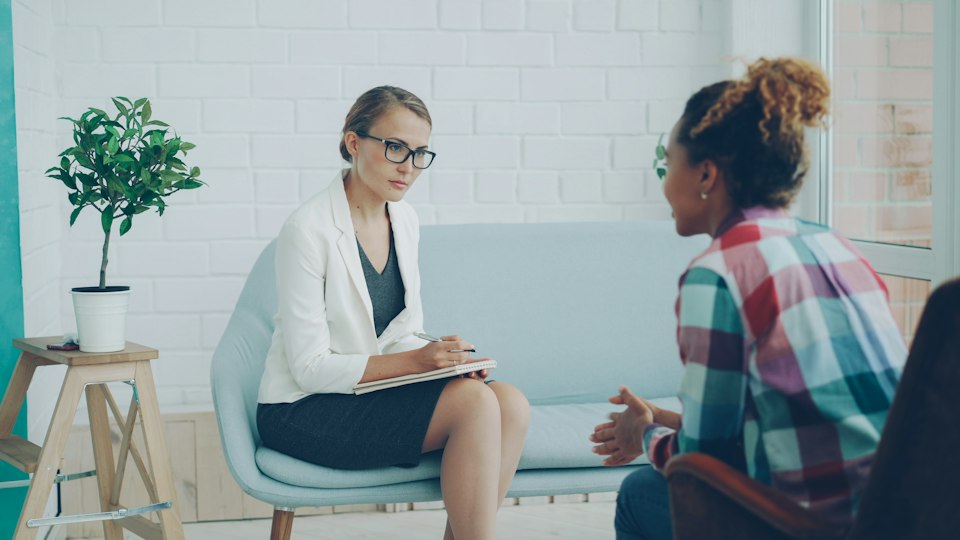 相談相手の話を聞きながらメモを取る女性